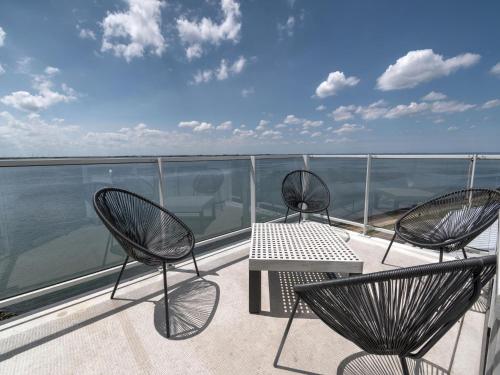 two chairs and a table on a balcony with the water at Apartment in Scherpenisse by Oosterschelde in Scherpenisse
