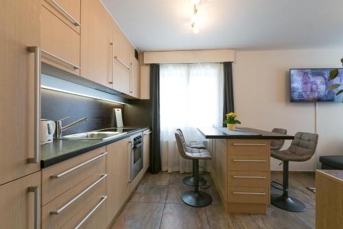 une cuisine avec un évier et une table avec des chaises dans l'établissement Spirit Apartments - Studio 2 - Küche - Parkplatz, à Engelberg