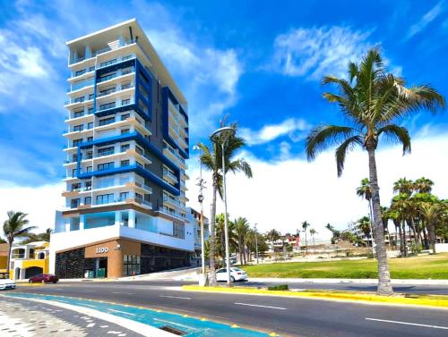 a tall building with palm trees in front of a street at Malecón de Mazatlan Vista al mar Alberca Infinity Jacuzzi Gym in Mazatlán