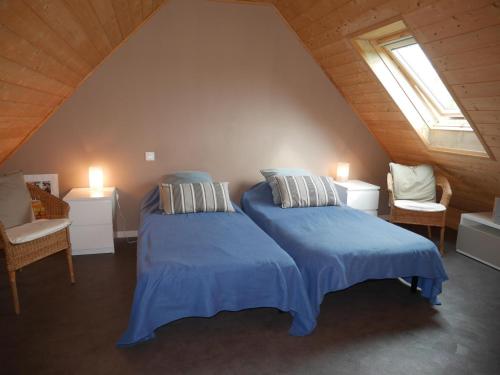 een slaapkamer op zolder met 2 bedden en 2 stoelen bij Wooden house near the sea, Landéda in Landéda