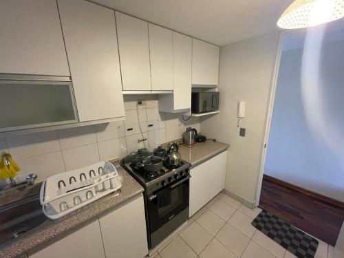 Una pequeña cocina con estufa y fregadero. en Departamento completo en Miraflores Surquillo, en Lima