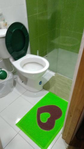 a bathroom with a toilet with a green sign on the floor at Parrot House San Antonio in Cali
