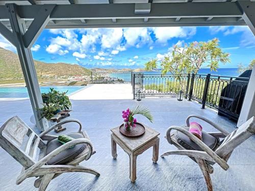 eine Terrasse mit 2 Stühlen, einem Tisch und Meerblick in der Unterkunft Frangipani Room in shared Villa Diamant, swimming pool, sea view in Grand Case
