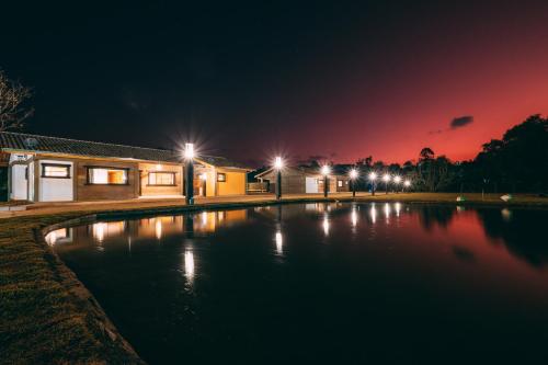 a swimming pool at night with lights on at Pousada Trem Chic in Poços de Caldas