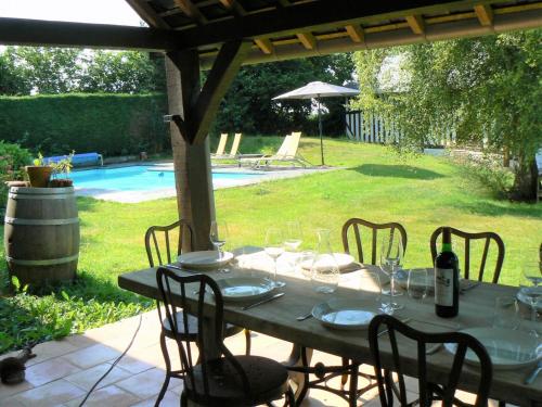 - une table avec des chaises et des verres à vin sur la terrasse dans l'établissement Estate in Normandy with Pool & Tennis Court, à Le Mesnil-sur-Blangy