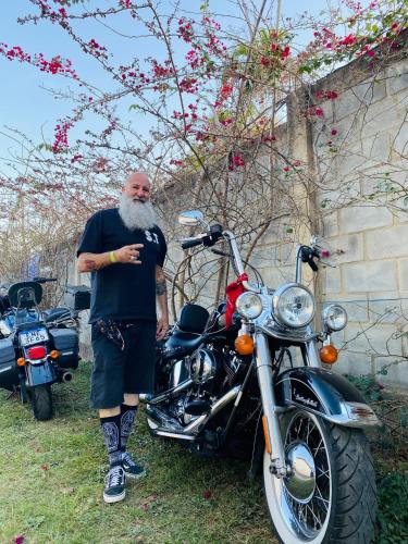 a man with a beard standing next to a motorcycle at POUSADA CHARLOTTE in Tiradentes