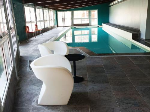 - une piscine avec 2 chaises blanches à côté de la piscine dans l'établissement Appartement T3 dans Château avec Piscine et Sauna à Jausiers, 6 pers, Terrasse et Balcon - FR-1-165B-4, à Jausiers