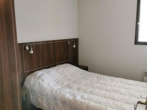 a bedroom with a white bed with a wooden headboard at Appartement Jausiers, 3 pièces, 6 personnes - FR-1-165B-20 in Jausiers