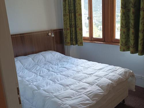 1 cama blanca en un dormitorio con ventana en Appartement Jausiers, 3 pièces, 6 personnes - FR-1-165B-32, en Jausiers