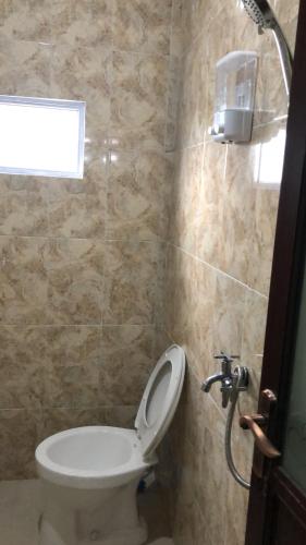 a bathroom with a white toilet and a window at Guest house Cemara in Pasuruan