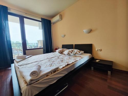 sypialnia z łóżkiem i dużym oknem w obiekcie Europroperties Zlatna Kotva Apartments w Złotych Piaskach