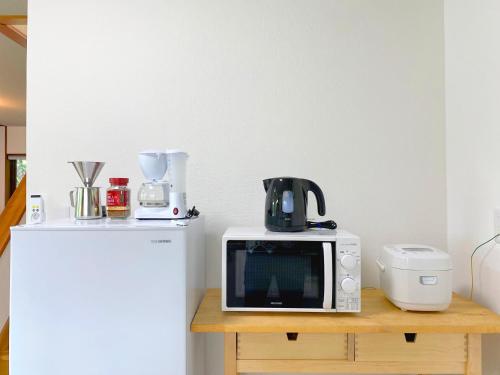 a microwave sitting on a table next to a refrigerator at R-house 1st in Oshino