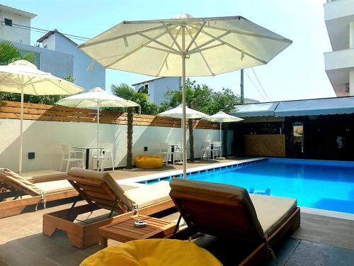 einen Pool mit Stühlen und Sonnenschirmen neben einem Pool in der Unterkunft Valmar Hotel in Ksamil