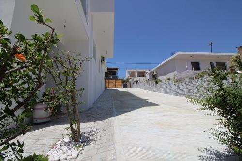 a walkway next to a white building with plants at Vila Ori in Ksamil