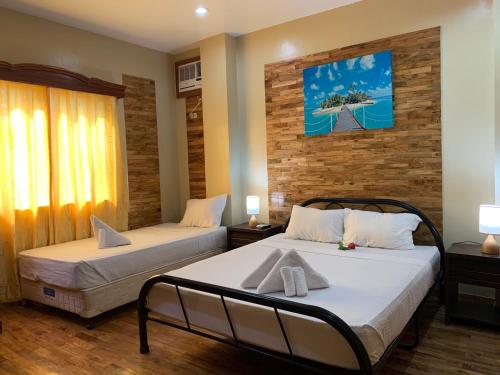 a bedroom with two beds and a painting on the wall at Mabini Hotel in Mambajao