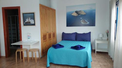 Un dormitorio con una cama con sábanas azules y una mesa. en APARTAMENTO ROQUE DEL ESTE en Orzola