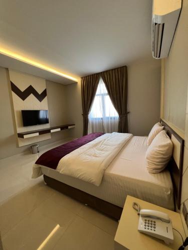 Aalia Hotel Suites في صحار: غرفة نوم بسرير ومكتب فيه تلفون
