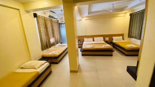 a room with three beds in it with yellow at Hotel Sai Gurusthan in Shirdi