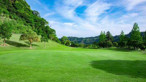 a golf course with a green field and trees at Kamogawa Country Hotel in Kamogawa