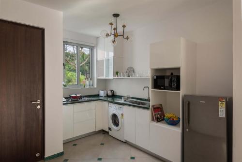 a kitchen with a refrigerator and a washing machine at El Arbol by The Blue Kite with Rooftop Pool, Kitchen, Wifi, Security,10 Mins to Candolim Beach & 5 mins to Casino in Panaji