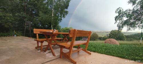 a wooden bench sitting at a table with a rainbow in the background at Mountain inn in Žabljak