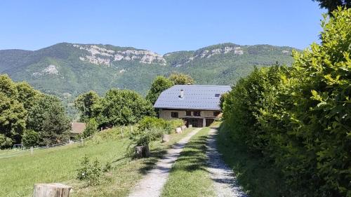 un camino de tierra que conduce a un edificio con montañas en el fondo en Les Praz en Montcel