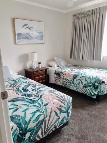 a room with two beds and a night stand and a window at Beachfront penthouse in Maroochydore