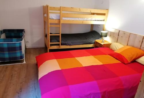 a bedroom with a colorful bed and bunk beds at Le grand duc in Mijoux