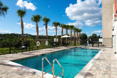 a swimming pool with palm trees in the background at Holiday Inn Express Orlando - South Park by IHG in Orlando