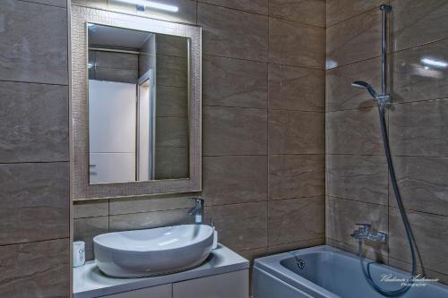 a bathroom with a sink and a mirror and a tub at Urbana Villa Four season in Zagreb