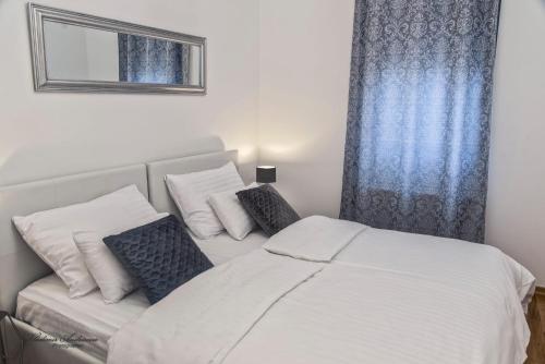 a bedroom with a white bed with pillows and a window at Urbana Villa Four season in Zagreb