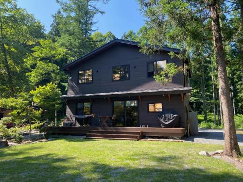 een zwart huis met een veranda en een tuin bij Hakuba Kaede House in Hakuba