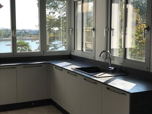 cocina con fregadero y algunas ventanas en Duplex vue sur tour Appartement Remparts 3, en La Rochelle