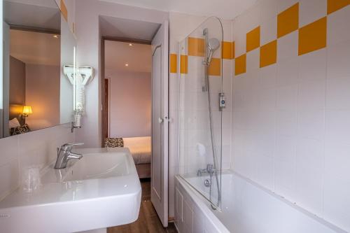 a bathroom with a sink and a tub and a mirror at The Originals City, Hôtel Régina, Périgueux in Périgueux