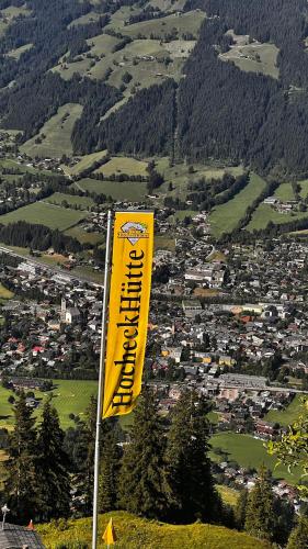 a yellow flag on top of a hill with a city at Hocheckhuette On Top of the Kitzbuehel Hahnenkamm Mountain in Kitzbühel