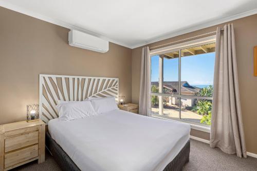 a bedroom with a bed and a window at Aqualuna Beach Resort in Coffs Harbour