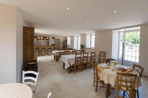 a dining room with tables and chairs and a kitchen at LA VALLEE JOLY in Le Vast