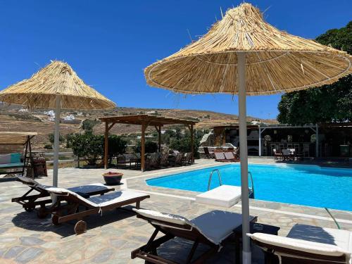 a pool with two straw umbrellas and chairs next to at Anna's Dreams in Parikia