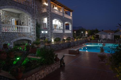 a large building with a swimming pool at night at Amalia Apartments in Stoupa