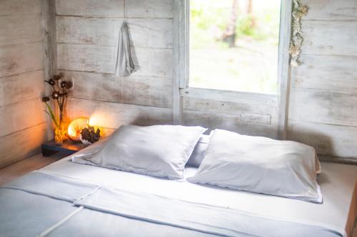 a bed with white sheets and a window in a room at Tailana Island Pulau Banyak in Alaban