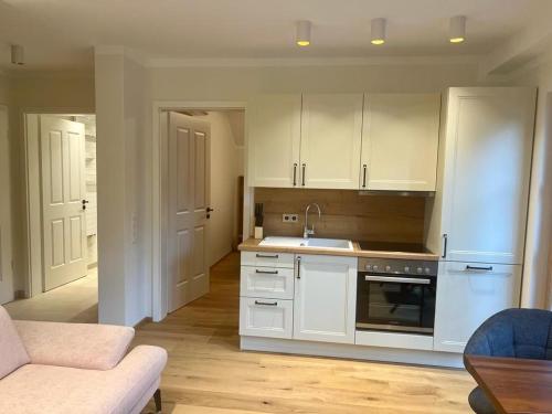 a kitchen with white cabinets and a sink and a couch at Gut Schwarz-n Hof Ferienwohnungen in Bad Griesbach