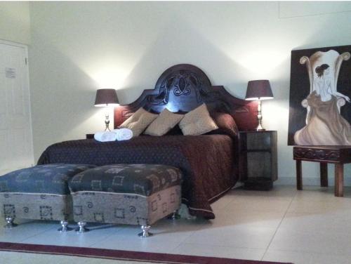 a bedroom with a large bed and a ottoman at The Homestead Margate - South Africa in Margate