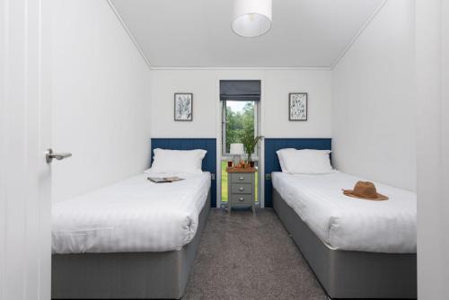 2 Betten in einem blau-weißen Zimmer in der Unterkunft Buttercup Lodge, 33 Roadford Lake Lodges in Lifton