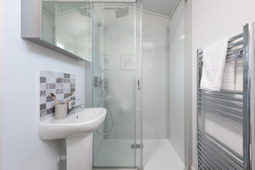 ein weißes Badezimmer mit Waschbecken und Dusche in der Unterkunft Buttercup Lodge, 33 Roadford Lake Lodges in Lifton