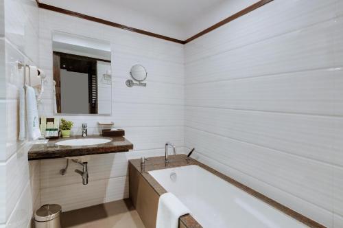 a white bathroom with a tub and a sink at The Fern Residency Turbhe in Navi Mumbai