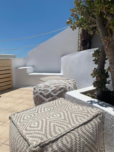 two ottomanchairs sitting on a patio with a tree at White Curves Santorini in Akrotiri