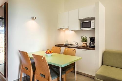 a kitchen and dining room with a green table and chairs at Maistra Select Petalon Resort in Vrsar
