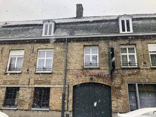 an old brick building with a garage in front of it at Hôtel - Restaurant Au Tonnelier in Bergues