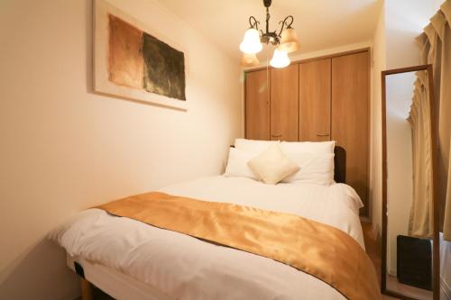a bedroom with a bed with white sheets and a chandelier at Kubotei in Sapporo