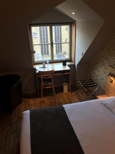 a bedroom with a desk and a bed and a window at Hôtel - Restaurant Au Tonnelier in Bergues
